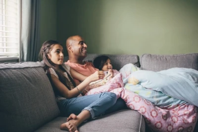 Mãe e pai brincando com bebê que está sentado sobre bancada.